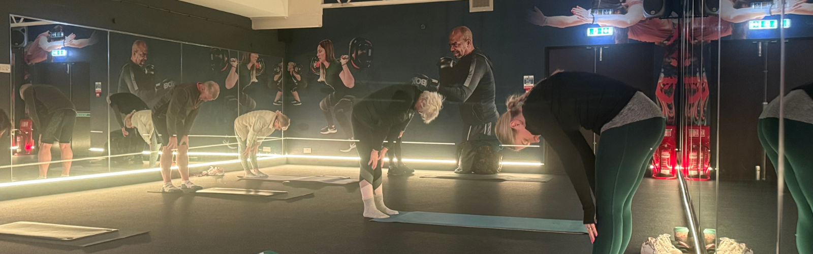 Members of a wellness class stretch together, bending forward on their mats in a modern studio designed for mindful fitness